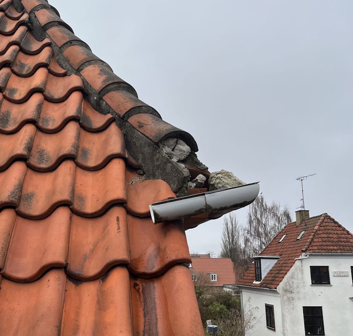 Smadret gratsten – når understrygning ikke er nok Ødelagt gratsten på tegltag – defekt rygning der kræver reparation af mørtel